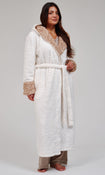 A woman wearing a plush white bathrobe with a leopard patterned hood and cuffs, posed against a neutral light gray background.