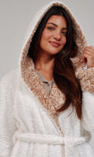 A woman wearing a plush white bathrobe with a leopard patterned hood and cuffs, posed against a neutral light gray background.
