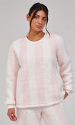 A woman modeling a fuzzy, sherpa-textured long-sleeve sweatshirt and matching sweatpants set in a light pink and white vertical stripe pattern, shot against a solid light gray studio background.