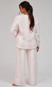 A woman wearing a light pink fuzzy fleece pajama set, shown from the back against a plain light gray studio background.