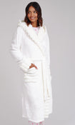 A woman wearing a plush white hooded bathrobe with faux-fur trim and front pockets, standing against a light gray studio background.